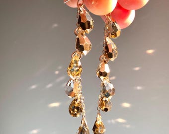 May include: Gold tone dangle earrings with multiple teardrop-shaped crystals.
