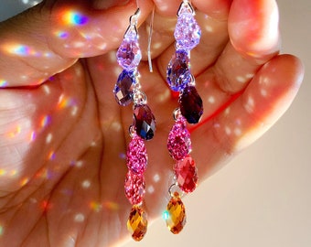 Può includere: Un paio di orecchini pendenti in argento con un gradiente di cristalli a forma di goccia di colore viola, rosa e arancio.