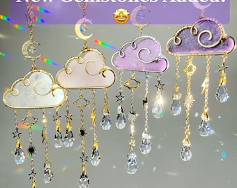 May include: Four hanging cloud-shaped suncatchers with gold and silver chains. Each cloud features a different color and design, with dangling crystal teardrops, stars, and lightning bolts. The text "New Gemstones Added!" is displayed across the top.