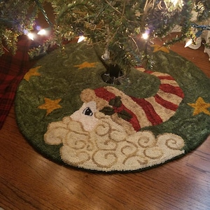 May include: A green and white Christmas tree skirt with a whimsical design of a white cloud with a red and white striped stocking. The skirt is decorated with gold stars.