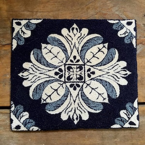 May include: A navy blue rug with a white and blue floral design. The rug is square shaped and has a geometric pattern.