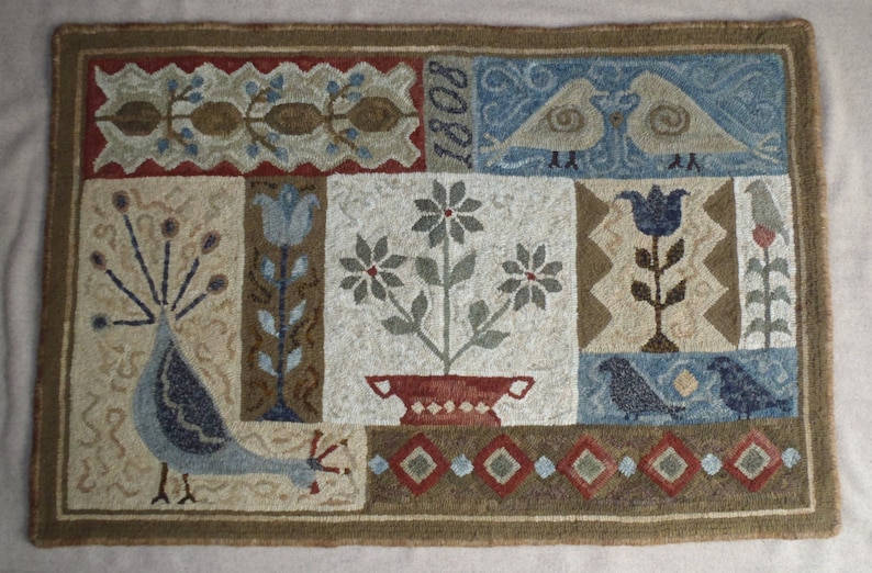 May include: A brown and beige hooked rug with a patchwork design. The rug features a peacock, flowers, birds, and the year "1808" in the top right corner.