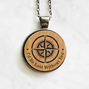 Op de afbeelding: Een houten kompas ketting met een zilveren ketting en de inscriptie "I'd Be Lost Without You" rond het kompas.