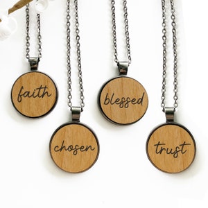 Puede incluir: Cuatro collares de plata con colgantes redondos de madera. Cada colgante tiene una palabra diferente grabada: fe, bendecido, elegido y confianza.