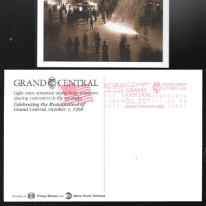 May include: A vintage postcard featuring a black and white photograph of Grand Central Station in New York City. The image shows the interior of the station with sunlight streaming through the large windows. The text on the postcard reads "GRAND CENTRAL" and "Celebrating the Rededication of Grand Central, October 1, 1998".
