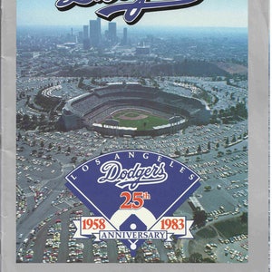 May include: A commemorative yearbook for the Los Angeles Dodgers 25th Anniversary, 1958-1983. The cover features an aerial view of Dodger Stadium with the city of Los Angeles in the background. The Dodgers logo is prominently displayed with the text "Los Angeles Dodgers 25th Anniversary 1958-1983". The text "Commemorative Yearbook" and "Three Dollars" is also included.
