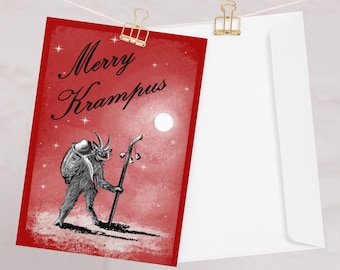 May include: A red greeting card with the words "Merry Krampus" in black script. The card features a Krampus illustration with a staff, set against a starry night sky and a full moon. The card is clipped to a white envelope.
