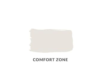 May include: A light beige paint swatch with a rectangular shape and brushstroke texture. The words "COMFORT ZONE" are printed in dark grey beneath the swatch, set against a white background.