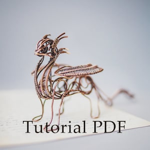 May include: A copper wire dragon sculpture with wings outstretched, standing on a piece of paper with the text "Tutorial PDF".