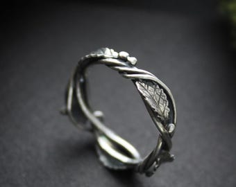 Può includere: Un anello d'argento con un designo a vite tortuoso e un dettaglio a foglia. L'anello è realizzato in argento sterling ed è un gioiello unico e delicato.