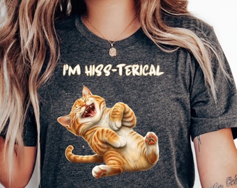May include: A gray t-shirt with the text "I'm hiss-terical" printed on it. A cartoon orange tabby cat is laughing hysterically on the shirt.
