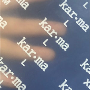 May include: A close-up of a blue surface with the word "kar-ma" repeated in white text.