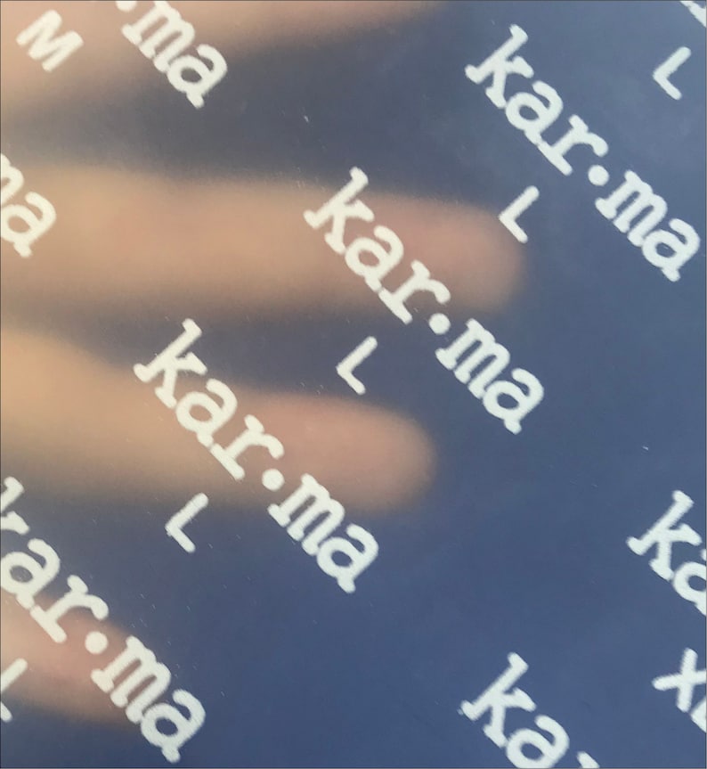 May include: A close-up of a blue surface with the word "kar-ma" repeated in white text.