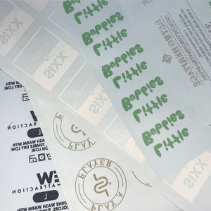 May include: Close-up of white and green stickers with the text "SIXX" and "Berries Little" repeated multiple times. The stickers are on a white background.