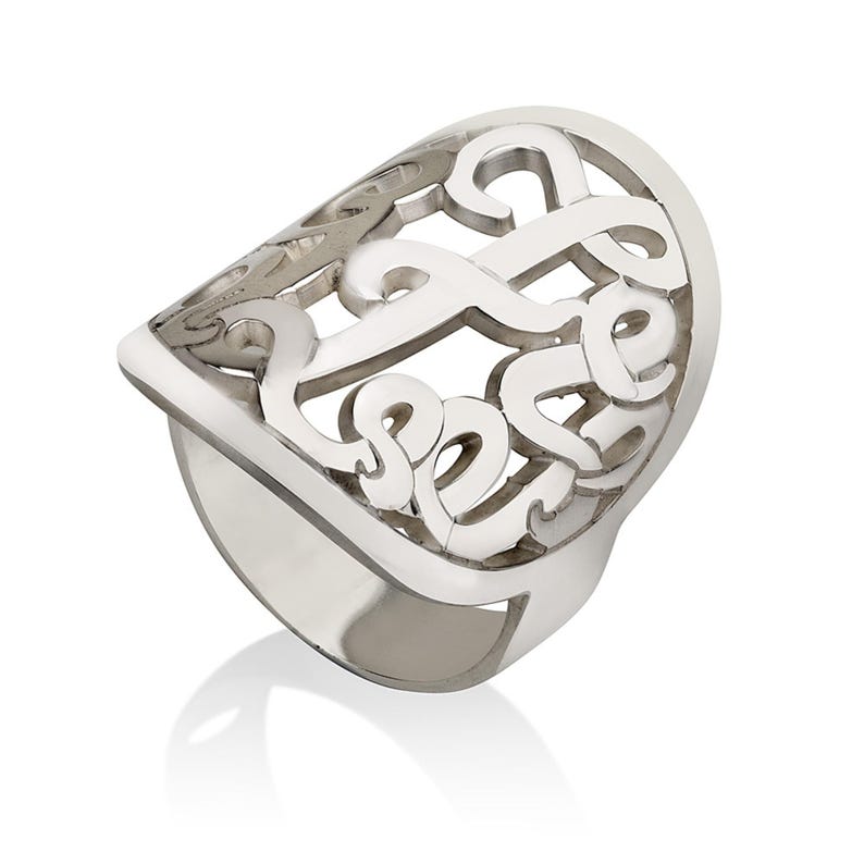 Op de afbeelding: Een zilverkleurige ring met een sierlijk, opengewerkt ontwerp. De ring heeft een grote, gebogen bovenkant met een wervelend patroon en een dikke band. De ring wordt getoond op een witte achtergrond, met een lichte reflectie.