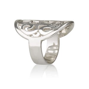 Op de afbeelding: Een zilveren ring met een open ontwerp. De ring heeft een brede, halvemaanvormige bovenkant met een wervelend filigraanpatroon. De band is effen en glad, tegen een witte achtergrond.