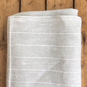 May include: A light gray throw blanket with white stitching in a horizontal stripe pattern.