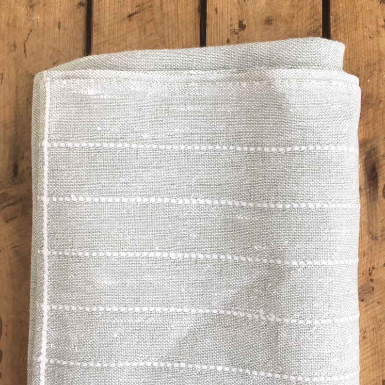 May include: A light gray throw blanket with white stitching in a horizontal stripe pattern.