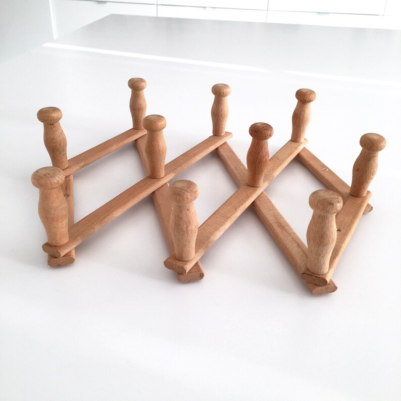 May include: A wooden coat rack with eight hooks, folded in a zig-zag pattern. The rack is made of natural wood and has a rustic look.