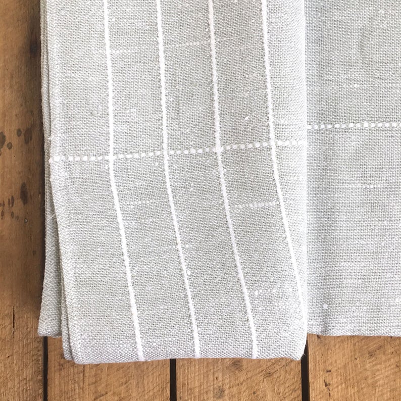 May include: A gray and white striped fabric with a subtle texture. The fabric is folded in half and the edges are visible.