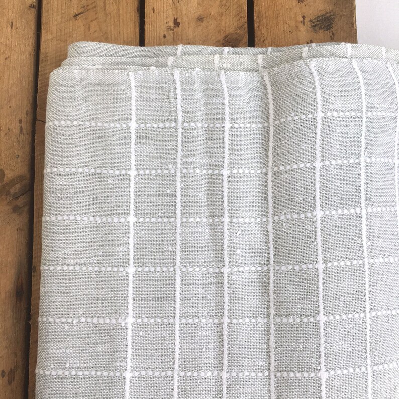 May include: A gray throw blanket with a white grid pattern. The blanket is made of a soft, woven fabric.