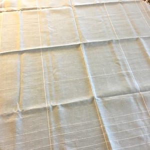 May include: A light gray tablecloth with a subtle white grid pattern. The tablecloth is made of a woven fabric with a slightly textured surface.