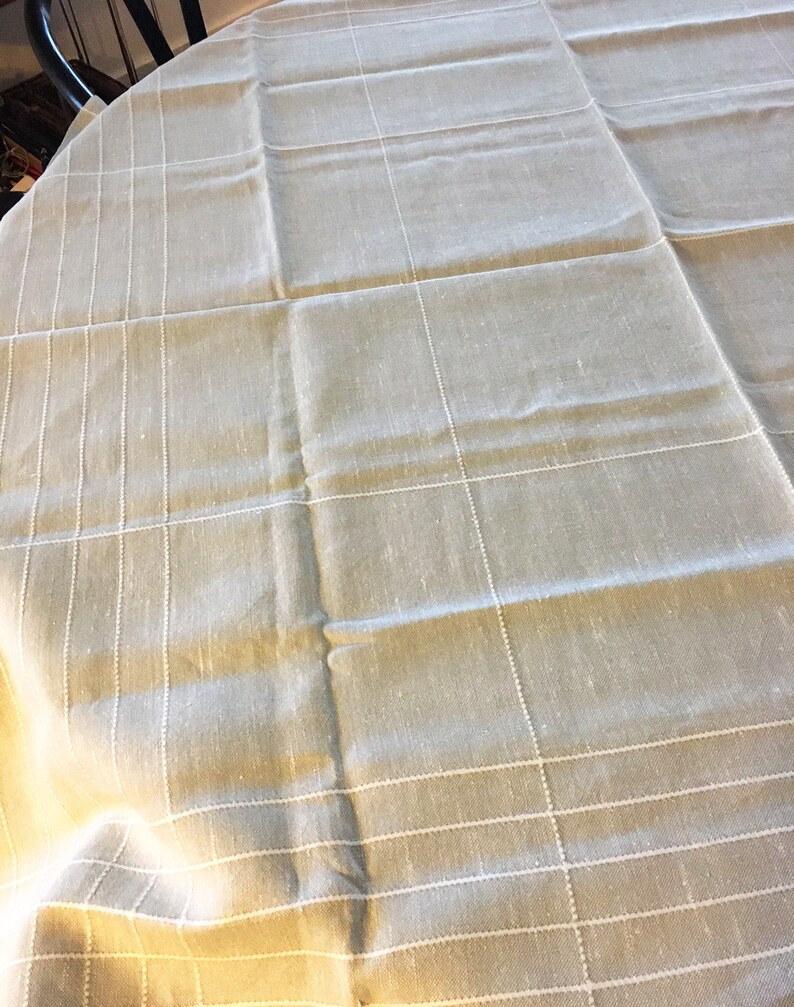 May include: A beige tablecloth with a white checkered pattern. The tablecloth is made of a linen-like material and has a slightly wrinkled texture.