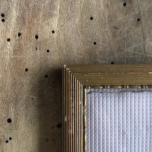 Może przedstawiać: Złota rama do obrazu z białym passe-partout i teksturą drewna w tle.