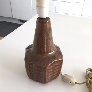May include: A brown ceramic table lamp with a geometric design and a white cord.