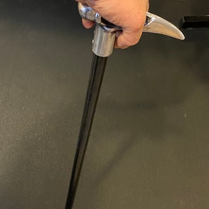 May include: A black walking stick with a silver metal handle shaped like a bird's head.
