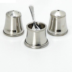 May include: A set of three silver salt and pepper shakers with a small spoon. The shakers have a round top and a bell-shaped base.