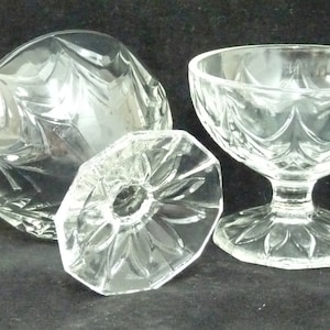 May include: Two clear glass dessert bowls with a cut glass design. The bowls have a wide, shallow bowl and a short stem.