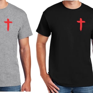 May include: Two short-sleeved t-shirts, one gray and one black, each featuring a red cross design on the upper left chest. The crosses have a brushstroke appearance. The shirts are plain and simple.