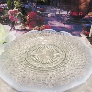 May include: A white milk glass serving plate with a scalloped edge and a clear glass center with a raised, sunburst design.