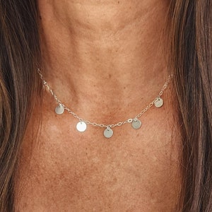 May include: A silver necklace with a delicate chain and multiple small round pendants.