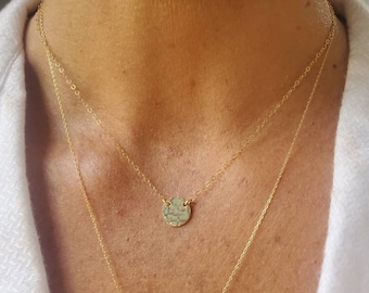 Peut inclure: Un collier en or avec un pendentif rond martelé. Le collier est superposé à une autre chaîne en or.