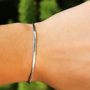 Puede incluir: Un brazalete de plata martillado en la muñeca de una persona.