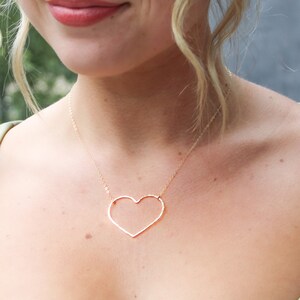 Puede incluir: Un collar dorado con un gran colgante de coraz&oacute;n abierto. El coraz&oacute;n est&aacute; hecho de metal martillado y tiene una forma ligeramente irregular.