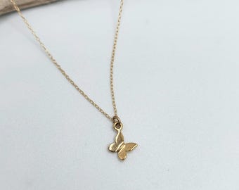 Pode incluir: Um delicado colar de corrente de ouro com um pequeno pingente de borboleta.