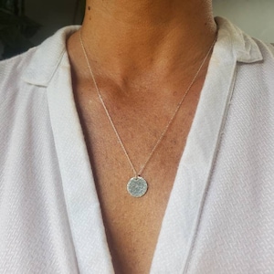 May include: A silver necklace with a hammered round pendant.