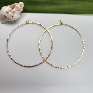 May include: A pair of gold hoop earrings with a hammered texture. The earrings are simple and elegant.