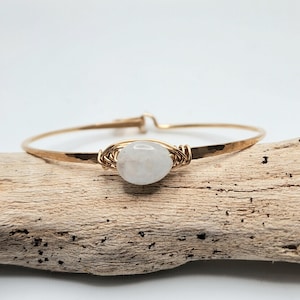 May include: A gold wire wrapped bracelet with a white moonstone bead.