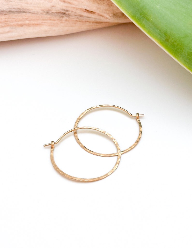 May include: A pair of gold hammered hoop earrings. The earrings are simple and elegant, and would make a great gift for any occasion.