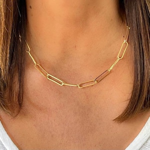 May include: A gold chain necklace with a simple, linked design. The chain is made of small, rectangular links.