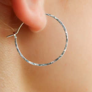 May include: Silver hoop earrings with a hammered texture.