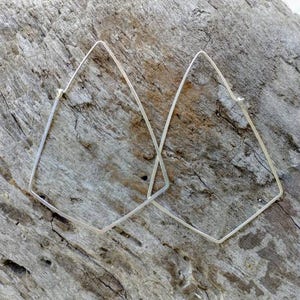 May include: A pair of silver geometric hoop earrings with a diamond shape. The earrings are made of thin wire and are lightweight.