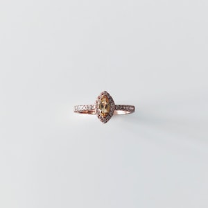 May include: A rose gold ring with a marquise-shaped topaz gemstone surrounded by a halo of smaller diamonds.