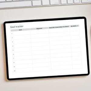 Può includere: Un tablet digitale che mostra un modello di "Goal tracker", insieme a uno stilo bianco e un taccuino a spirale. Il tablet è su una superficie bianca, con una tastiera e del verde sullo sfondo. Il modello include campi per obiettivi e scadenze.