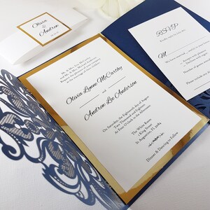 May include: A navy blue and gold wedding invitation with a laser-cut design. The invitation features the names Olivia Lynne McCarthy and Andrew Lee Anderson, the date and time of the wedding, and the location. The RSVP card is also included.