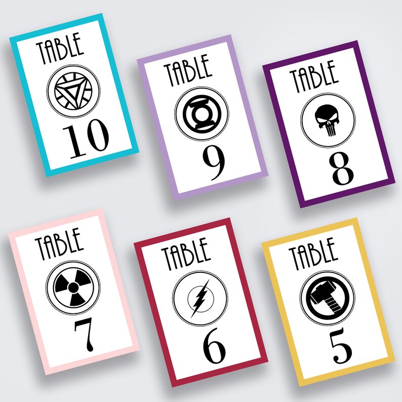 May include: Ten table number cards featuring superhero logos and numbers 5 to 10. The cards are in various colours: yellow, red, purple, pink, blue, and light purple.